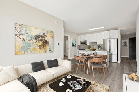 A modern living room with a white couch and a large abstract painting on the wall.