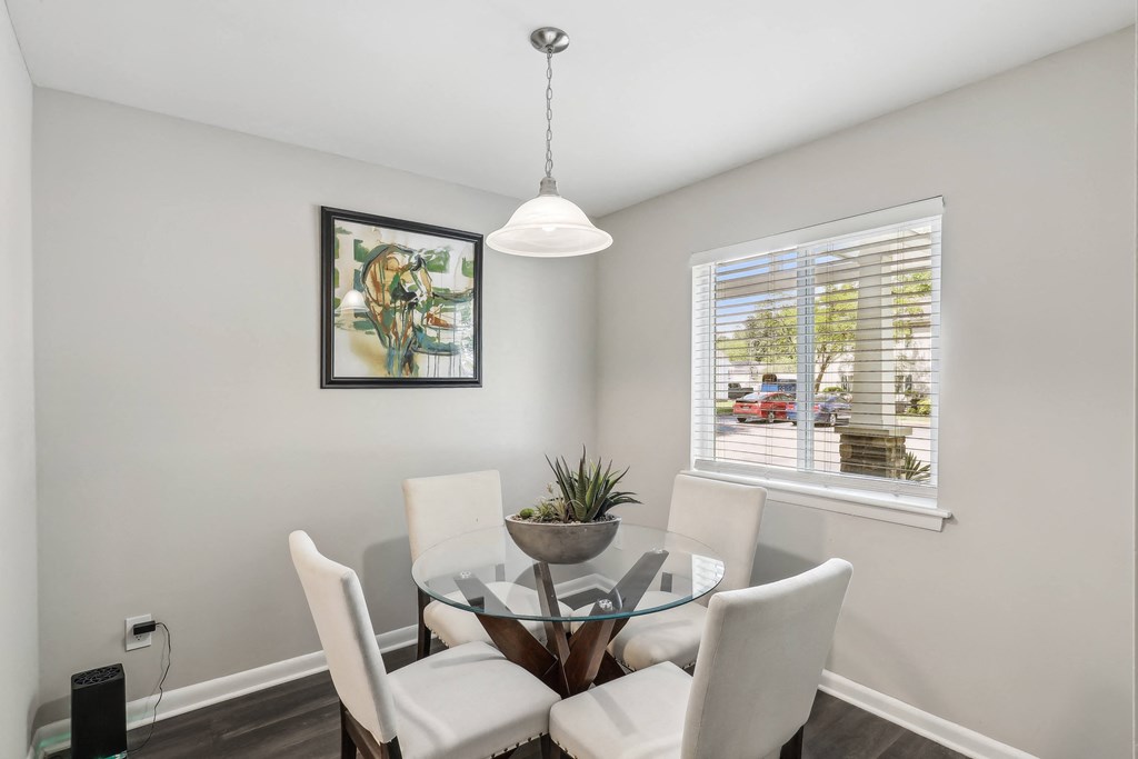 a dining room with a glass table and chairs and a window