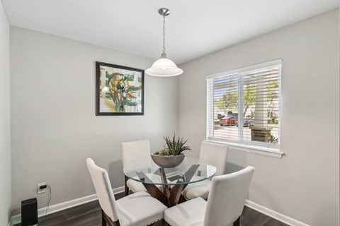 a dining room with a glass table and chairs and a window