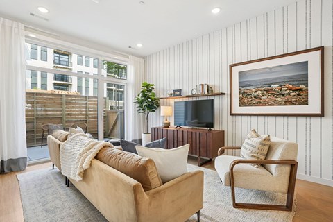 A living room with a tan couch, a chair, and a painting on the wall.