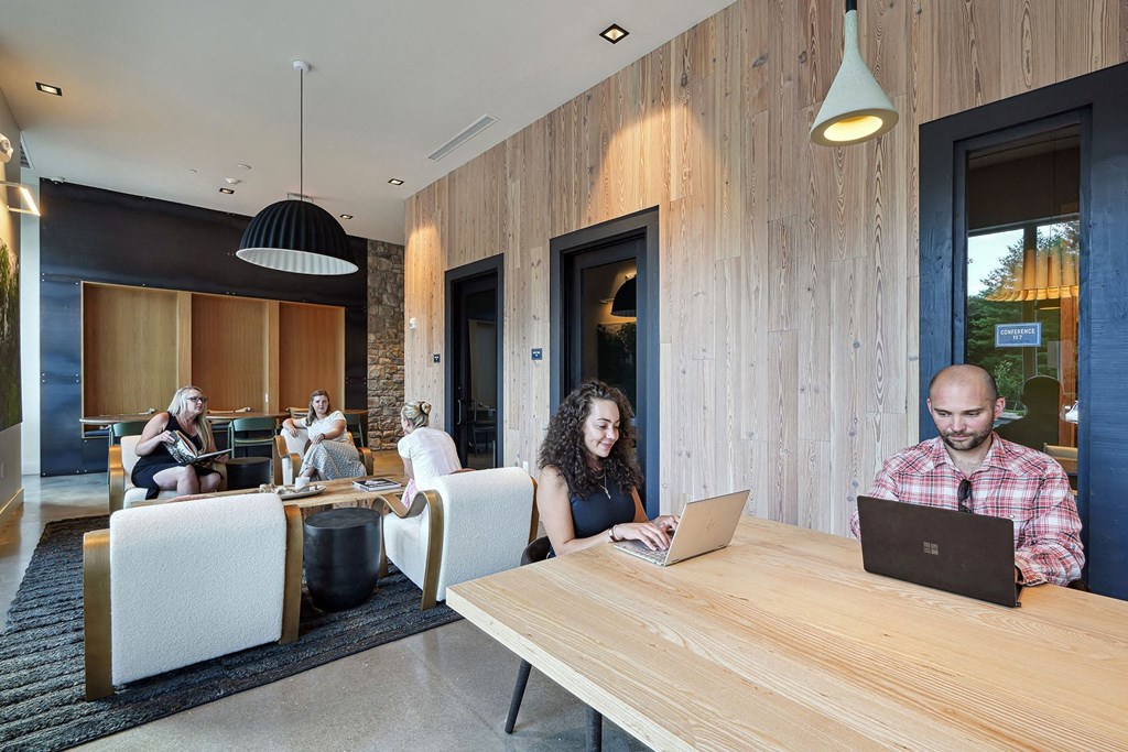 people sitting at tables in a lobby with laptops