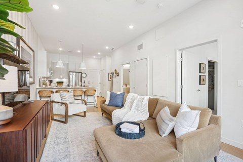 A living room with a beige couch and a wooden table.