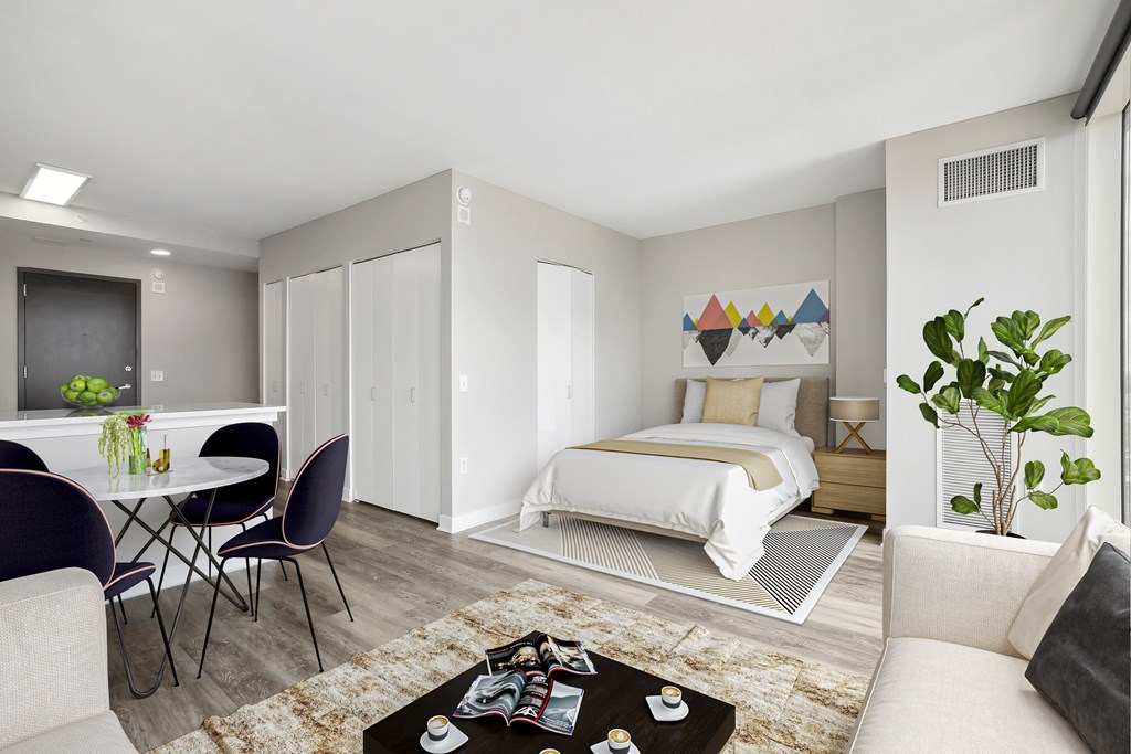 A modern bedroom with a bed, a couch, a dining table, and a rug.