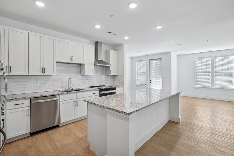 A kitchen with white cabinets and a granite countertop.
