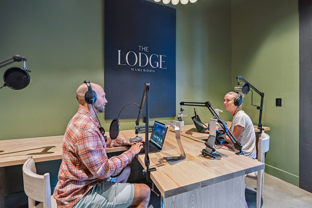 two men sitting at a table with microphones and laptops