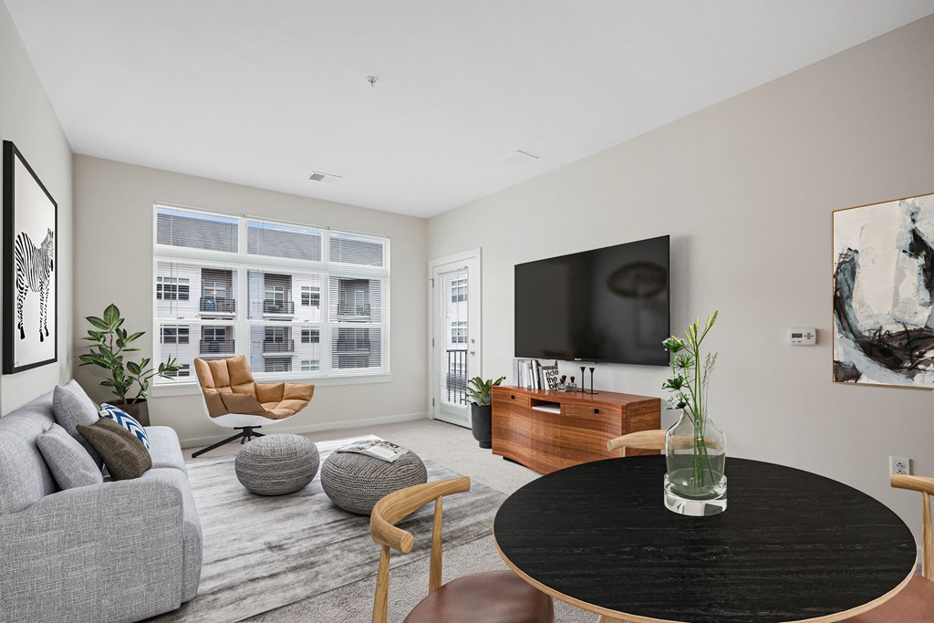 a living room with a large tv on the wall and a round coffee table in the middle