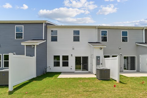 A grey house with a white fence and two air conditioning units.