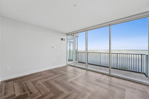 A room with a wooden floor and a balcony with a railing.