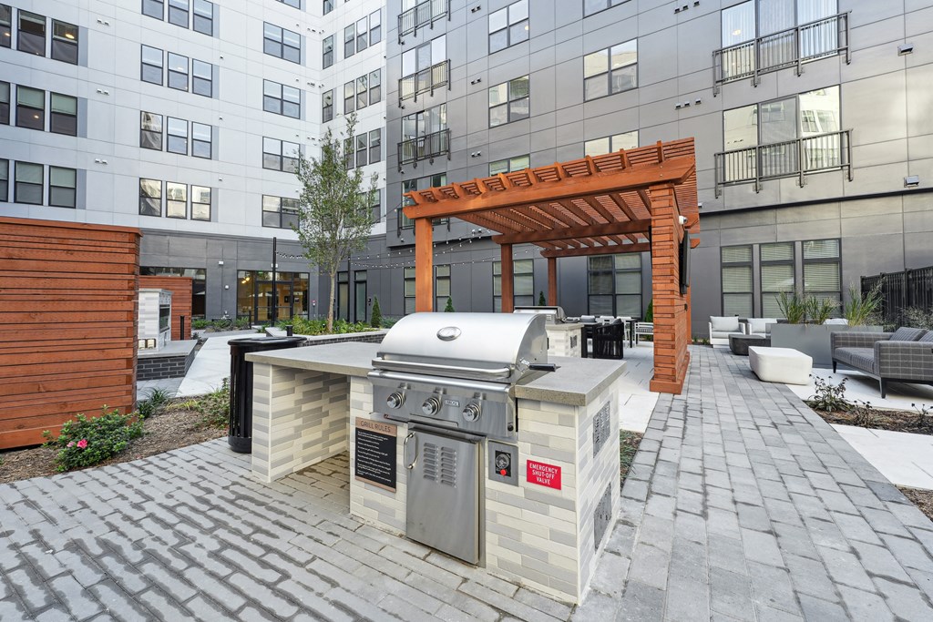 a patio with a grill and a barbecue area in front of an apartment building