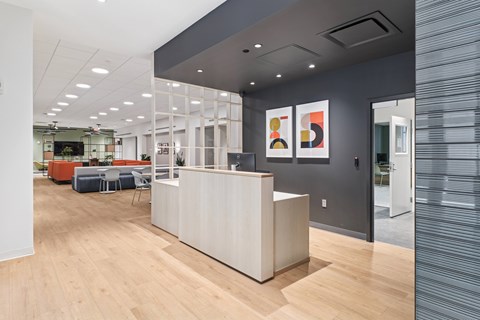 A reception area with a white counter and orange chairs.