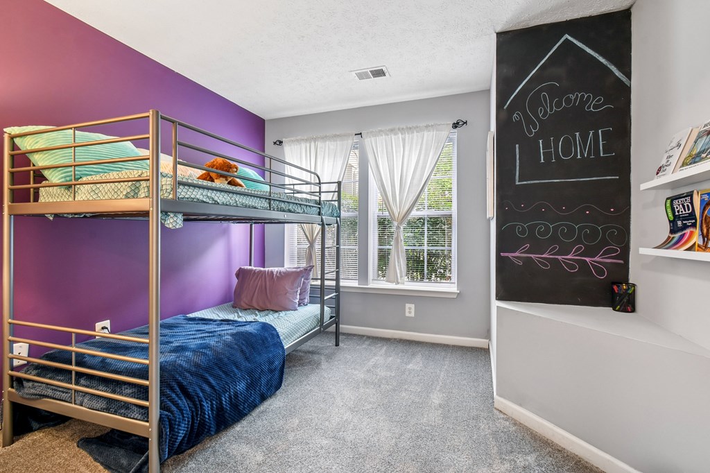 A bedroom with purple walls and a bunk bed.