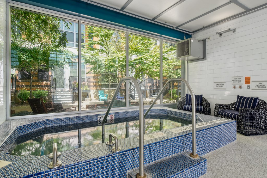 A blue tiled pool with a diving board in a room with a window.