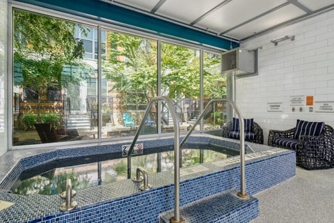 A blue tiled pool with a diving board in a room with a window.
