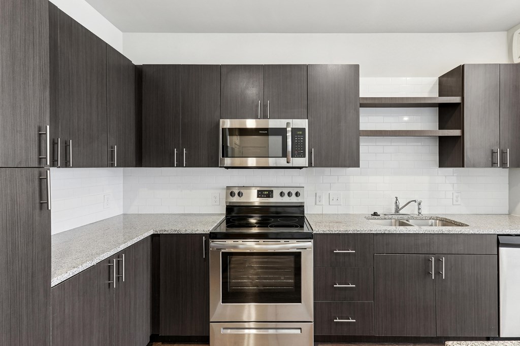 A modern kitchen with dark wood cabinets and stainless steel appliances.