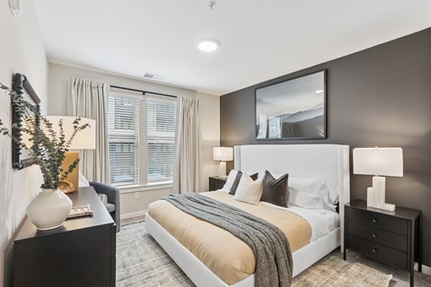 A bedroom with a large bed, a nightstand with a lamp, and a mirror above the bed.