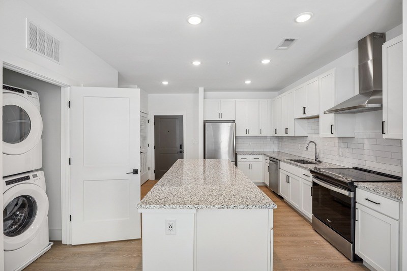 A modern kitchen with white cabinets and appliances.