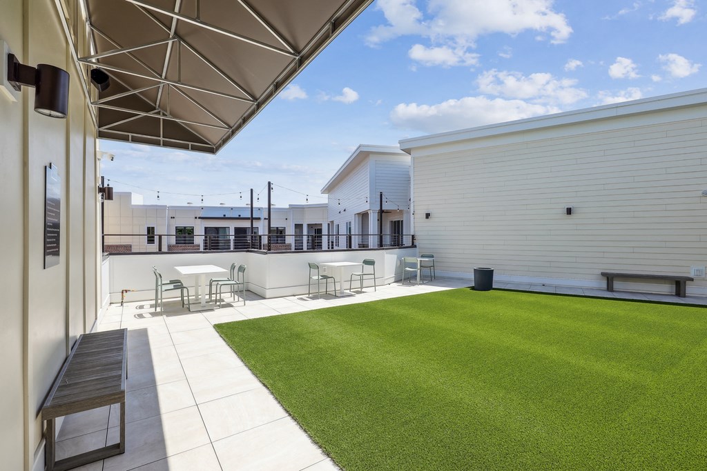 the yard of a building with a lawn and tables and chairs