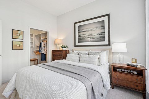 A bedroom with a large bed, a nightstand, and a painting on the wall.