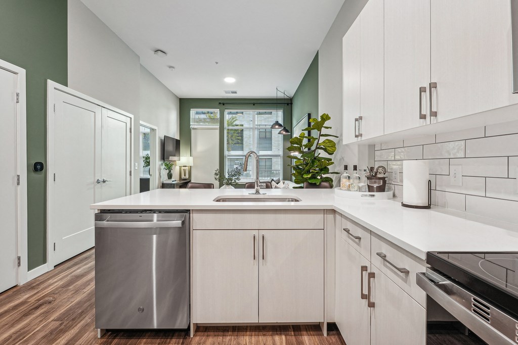 an open kitchen with white cabinets and a sink and a window