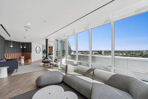 A modern living room with a large grey sofa and a view of the city.