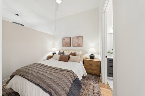 A bedroom with a large bed and a rug on the floor.
