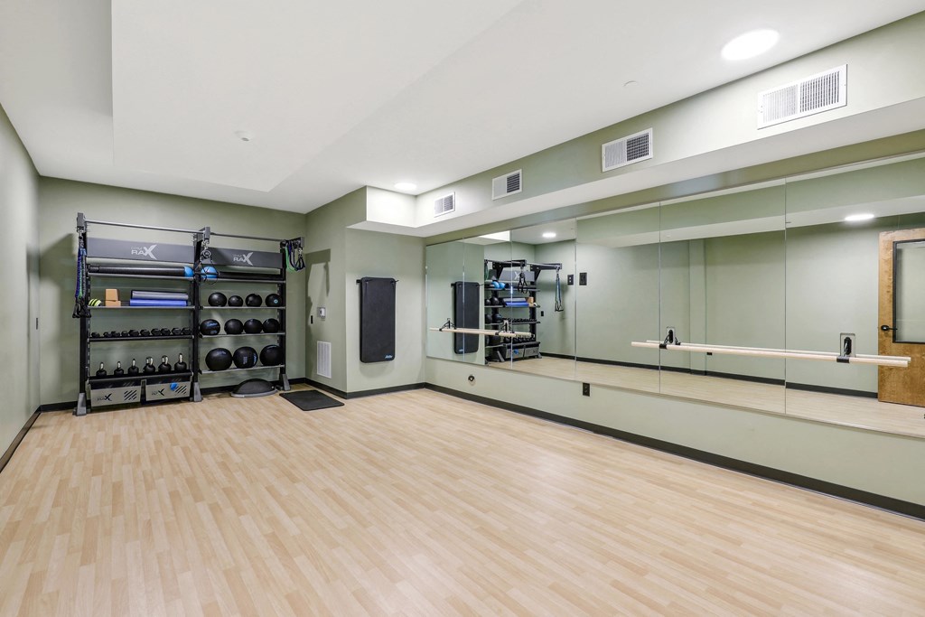 the spacious dance room with mirrored walls and a wood floor