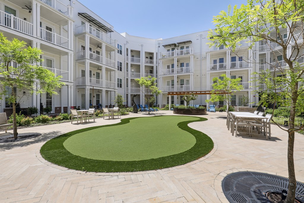 a courtyard with a green lawn in front of an apartment building