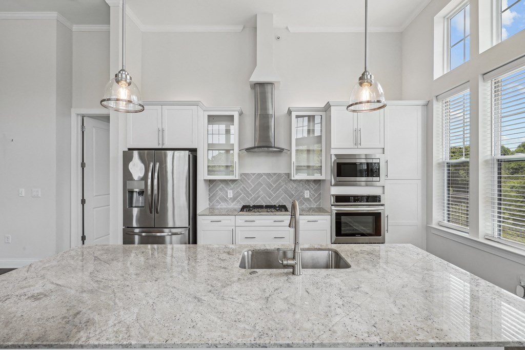 a kitchen with white cabinets and a marble counter top