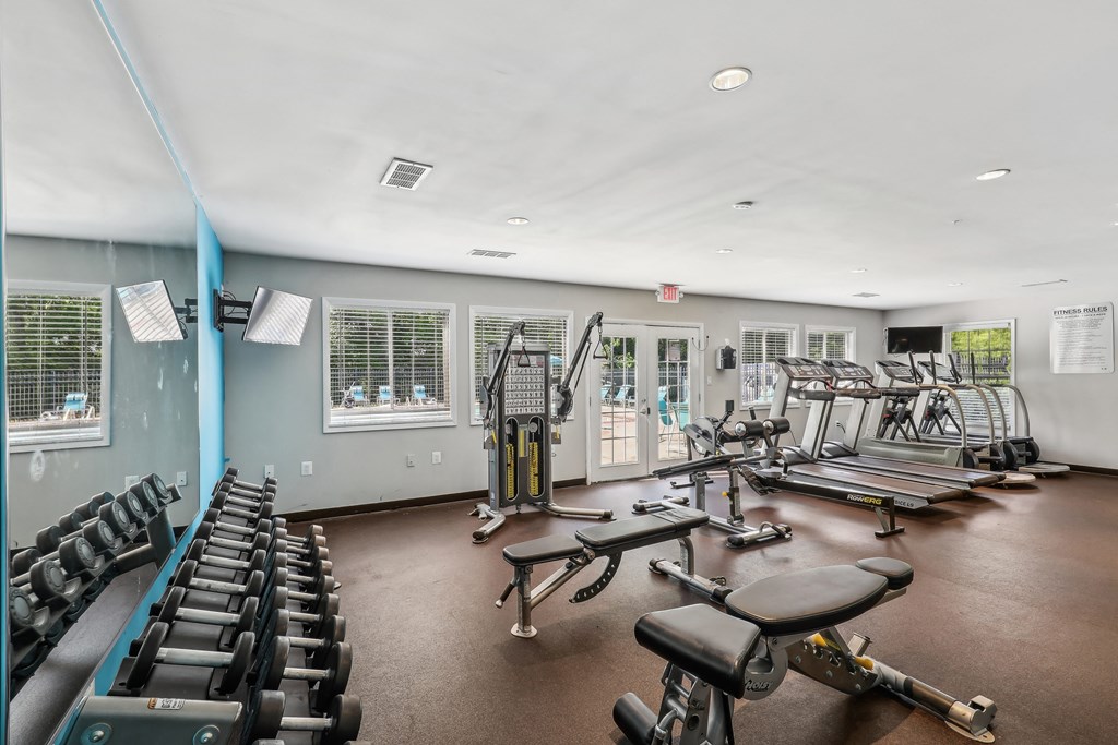 a fitness room with weights and cardio equipment and windows