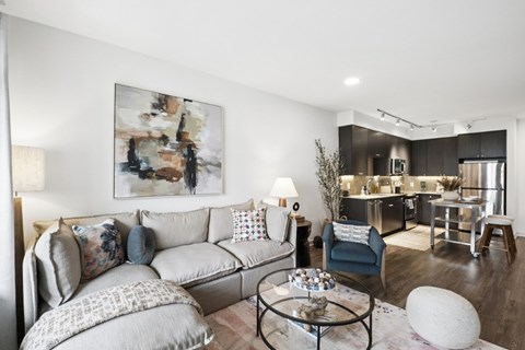 A modern living room with a grey sofa and a large abstract painting on the wall.