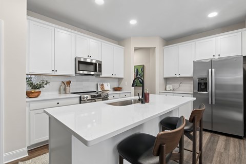 A modern kitchen with white cabinets and a large island.