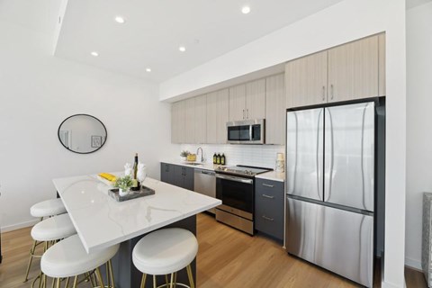 A modern kitchen with a white table and stools.