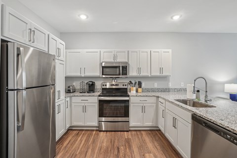 A modern kitchen with stainless steel appliances and wooden floors.