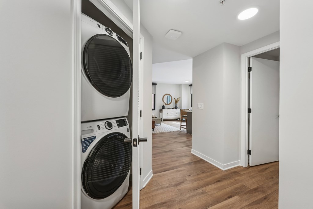 A white washing machine is open in a room with wood flooring.