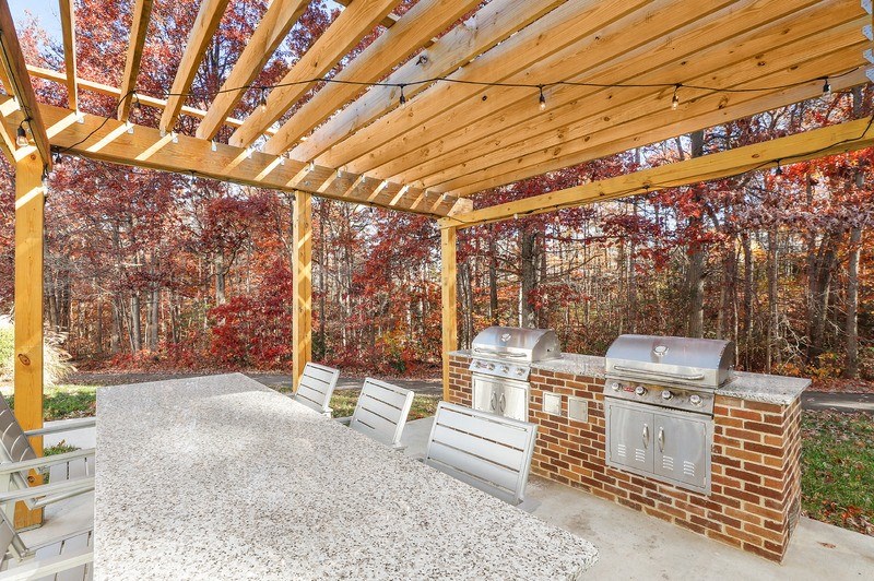 a patio with a barbecue grill and a table with chairs