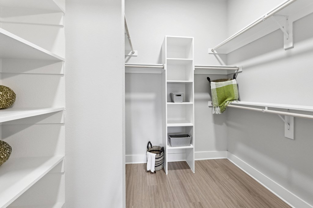 A white closet with shelves and a green pillow.
