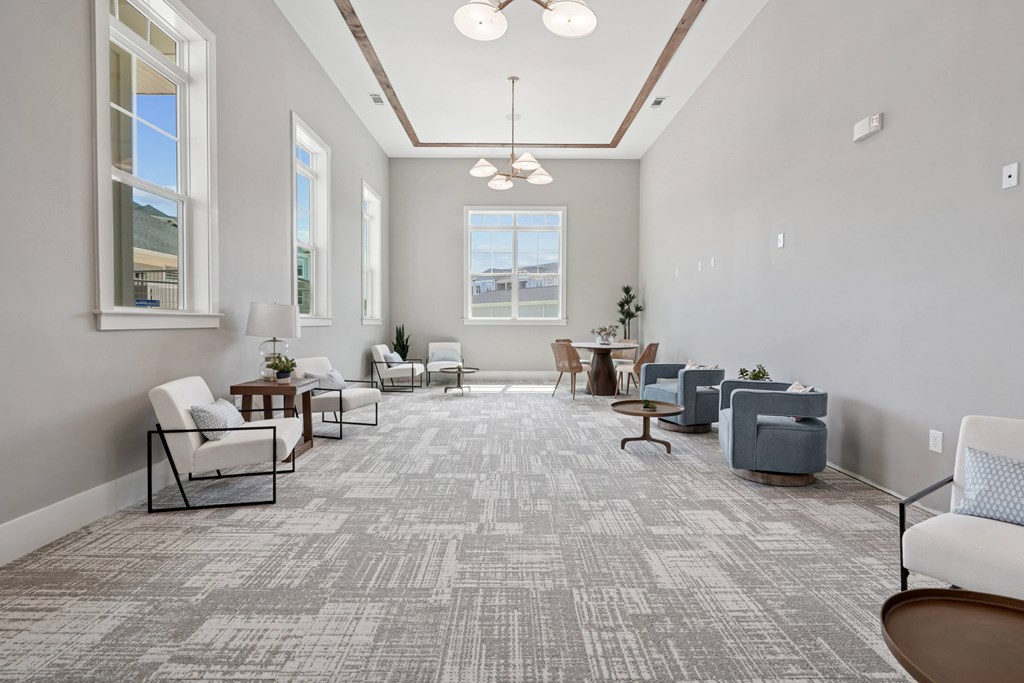 A spacious waiting room with grey carpet and white chairs.