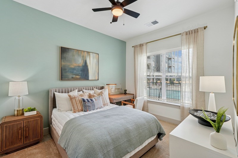 A bedroom with a large bed and a ceiling fan.