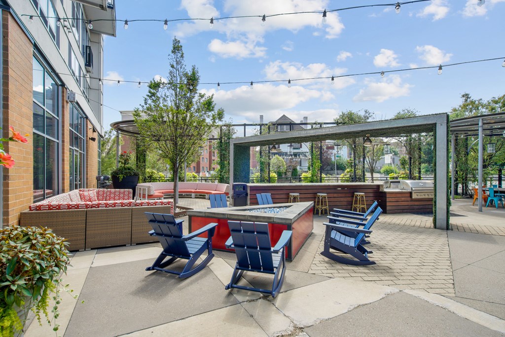 A patio with blue chairs and a table is surrounded by buildings.