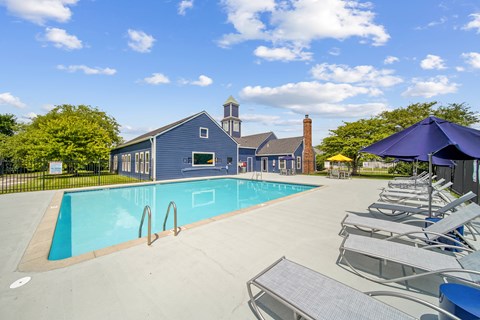 A pool with a blue umbrella and chairs.
