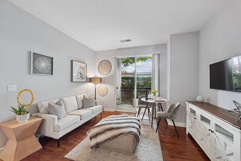 A living room with a white couch, a wooden coffee table, and a television on the wall.