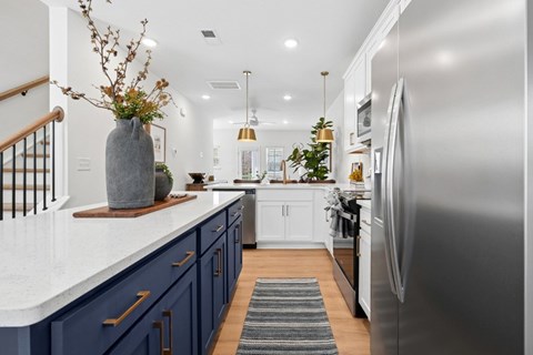 A modern kitchen with a stainless steel refrigerator and wooden flooring.