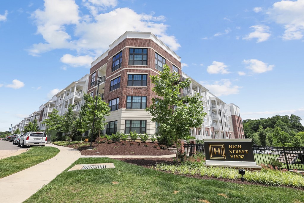 an apartment building with a sign for high street view on a sidewalk