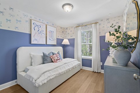 A bedroom with a white bed and a grey dresser.