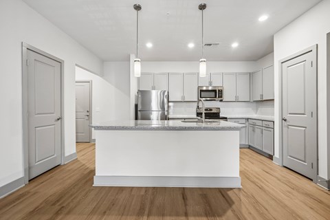 A modern kitchen with a white island and wooden floors.