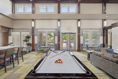 A pool table is in the middle of a room with a couch and chairs.