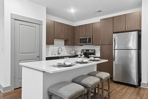 A kitchen with a white counter top and a stainless steel refrigerator.