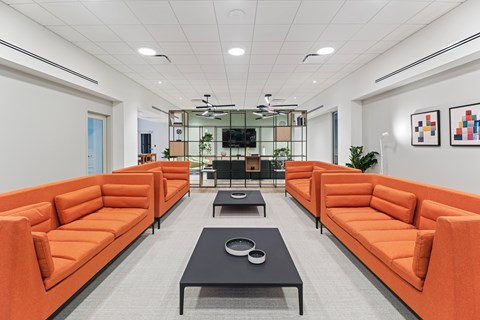A modern office space with orange couches and a black coffee table.