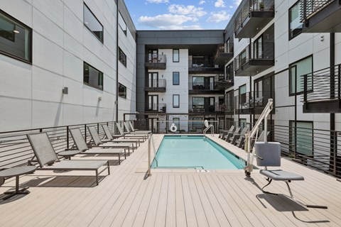 A pool surrounded by sun loungers on a wooden deck.