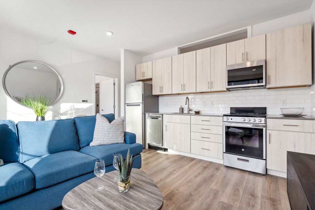 a living room with a blue couch and a kitchen with white cabinets